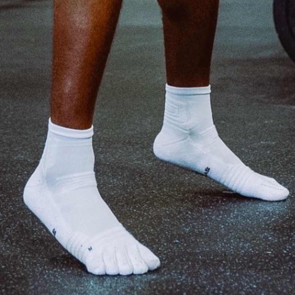 Athlete wearing white 1st ERA Performance Toe Socks with five-toe separation during gym training